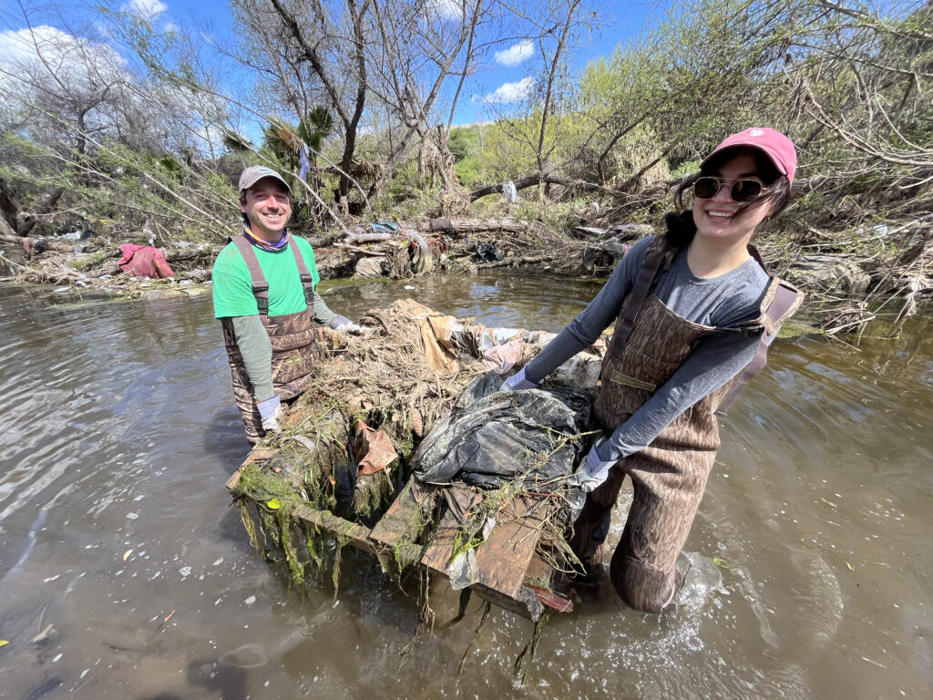 Clean Green ForesterCreek Two clean and green team members pull a large wooden pallet covered in weeds and trash out of the River.