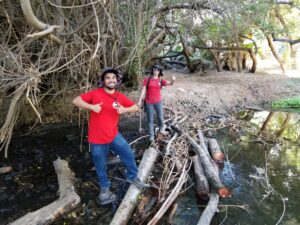 Two members of the river assessment field team give a thumbs up while crossing the river.