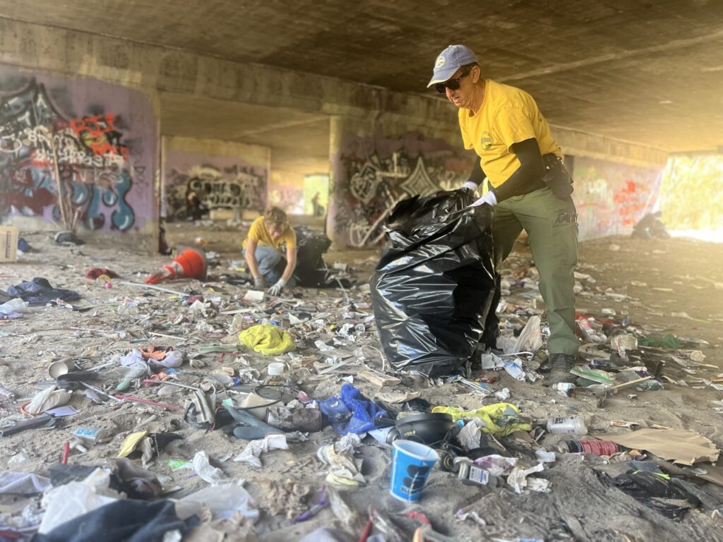 River Rescue trash pick up River Rescue team members clean up trash in the river bed, underneath a highway overpass.