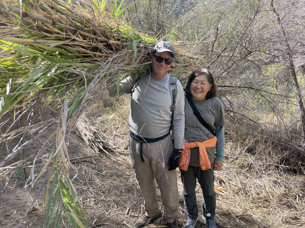 Watershed Services Invasive Plant Removal Volunteers A couple hold up invasive plant branches that they are removing fro the San Diego River Watershed.