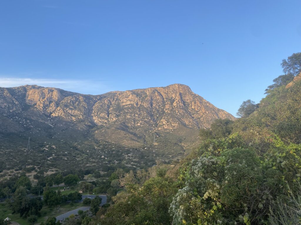 El Cajon Mtn The face of El Cajon Mountain set against a blue sky, with green trees in the foreground.