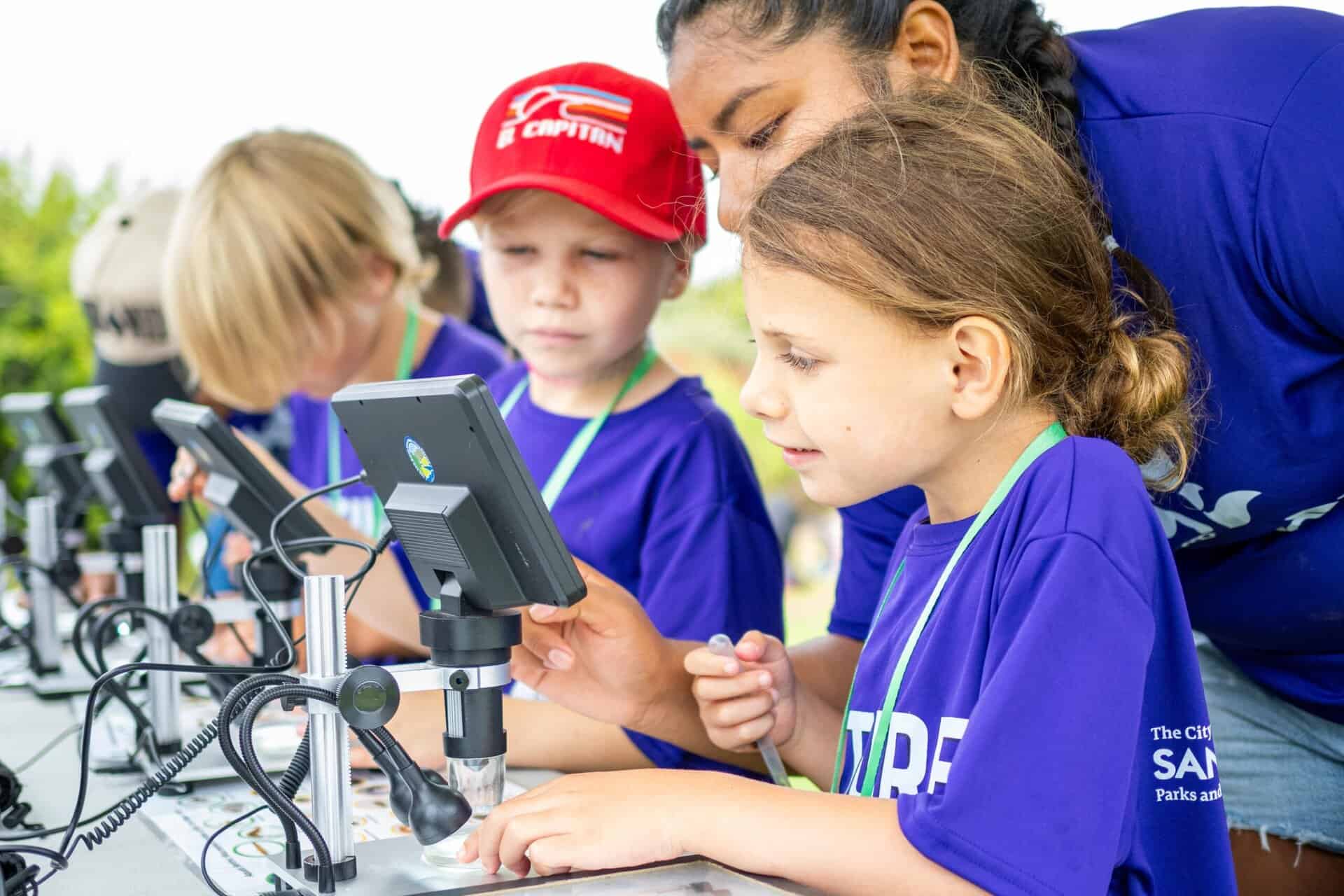 Kids use microscopes to view river water.