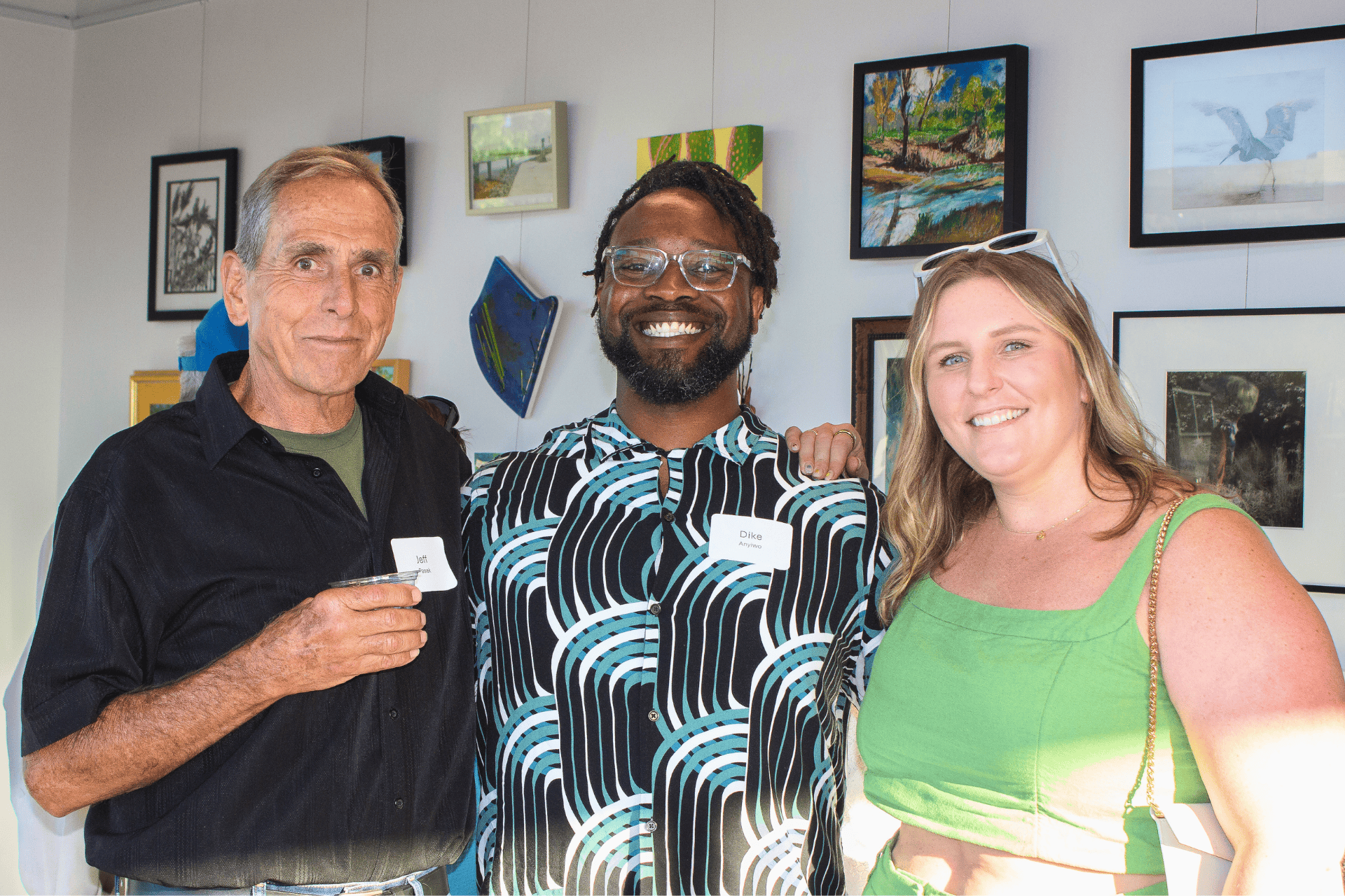 3 people standing in art gallery smiling with drinks