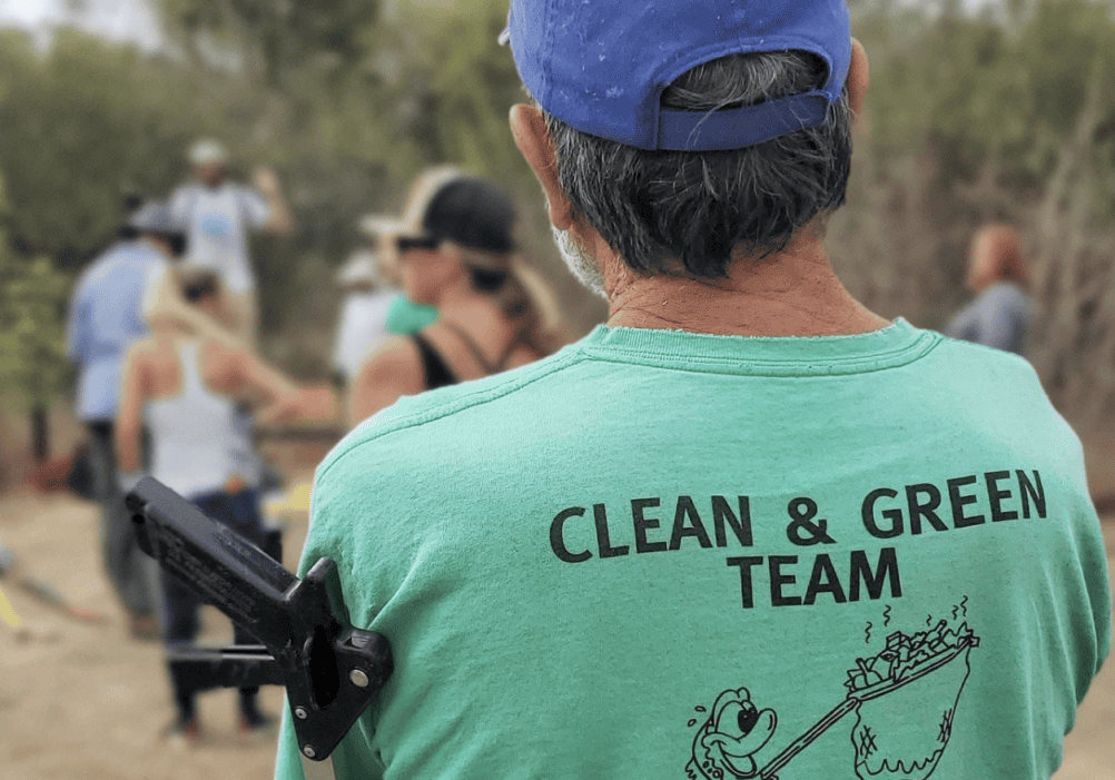 A person wearing a clean and green team shirt take a short break during a river clean up