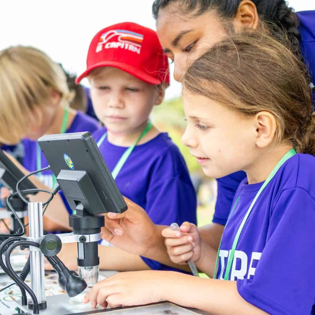 WATER RB Kids Using Microscopes 4 OB 2024 AP Kids use microscopes to view river water.